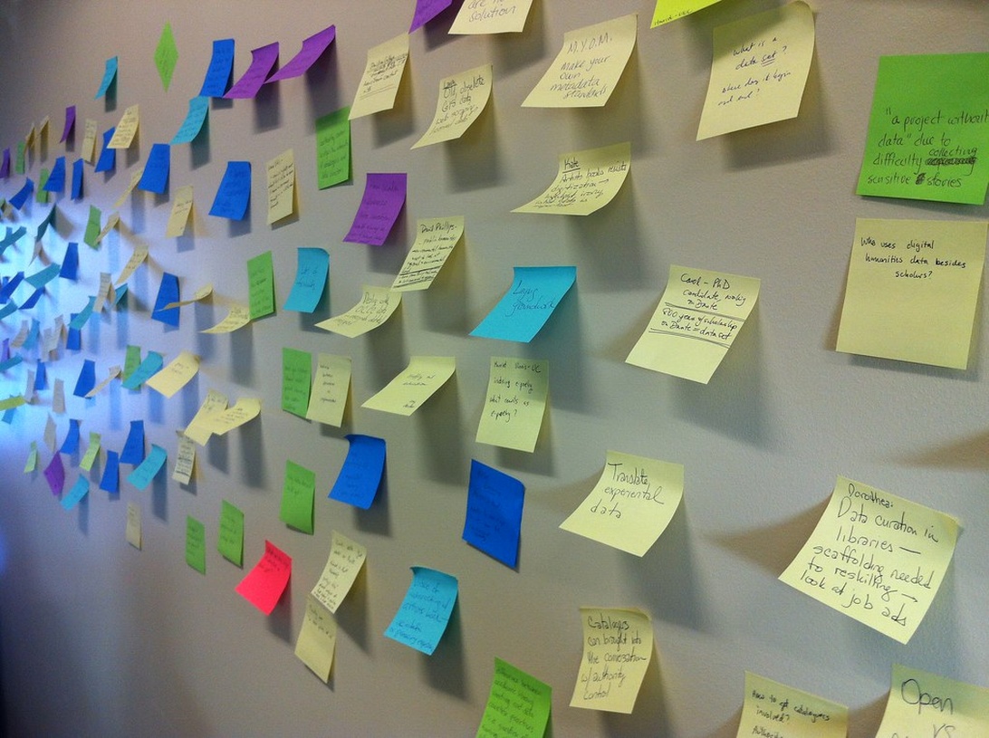 A wall covered with multicolored sticky notes representing a collaborative brainstorming session for a digital project.